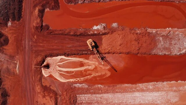 Aerial view of the mining of red clay. Industrial machines work in mining. Multicolored clay pattern