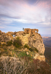 Fototapeta premium Vertical Dramatic view of Khornabuji castle with female tourist standing at the top and looking left