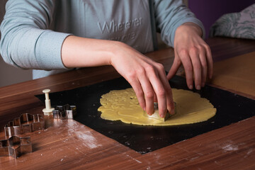 Young woman preparing christmas cookies on black baking sheet on table 