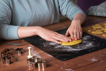 Young woman preparing christmas cookies on black baking sheet on table 