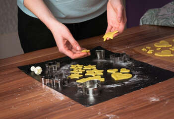 Young woman preparing christmas cookies on black baking sheet on table 