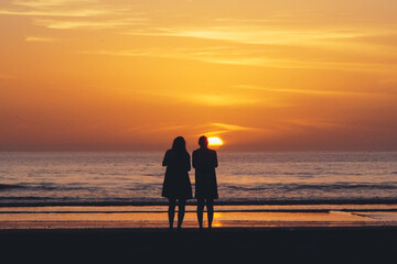 Surfers and people enjoying beach during sunset in Taghazout, Morocco