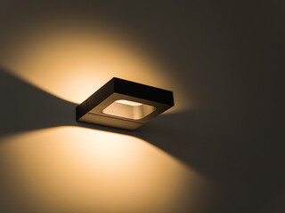 Sconce. Modern minimalist black square wall lamp shines with yellow light. Internal lighting....