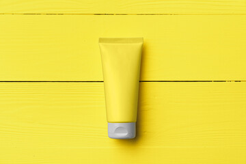 Yellow cream tube on yellow wooden background