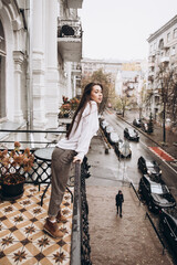 Fototapeta premium Photoshoot of a beautiful girl in a white shirt on the balcony