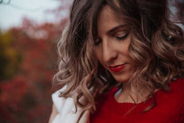 Naklejka premium cute girl in an autumn park with a delicate beige scarf smiles. autumn. falling leaves