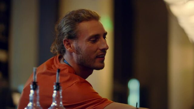 Handsome bartender accepting paypass payment indoors. Bar man smiling indoors.