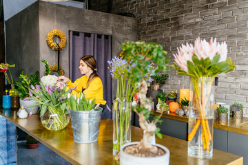 Caucasian woman florist make floral compositions for sale. Creative millennial female designer...
