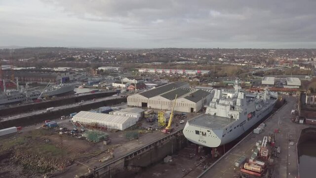 Cammell Laird British industry shipyard aerial view servicing military naval ship Birkenhead skyline orbit right reversing