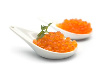 Closeup of trout eggs in a white ceramic spoon on white background
