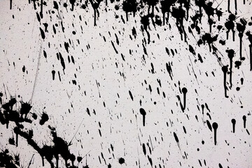 white cement wall with black spots of white paint. rough surface texture