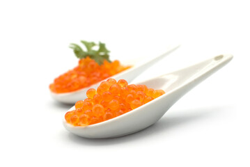 Closeup of trout eggs in a white ceramic spoon on white background