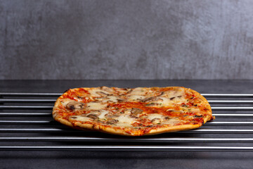 Metallic shiny grid with simple mushroom pizza with crunchy crest and golden yellow orange tint studio low key still life against a dark modern kitchen surface background