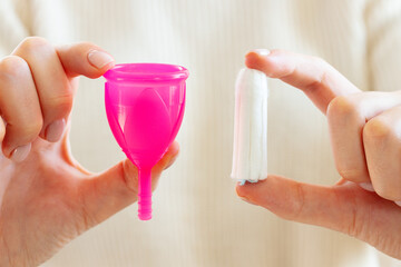 Female hands holding menstrual cup and medical tampon