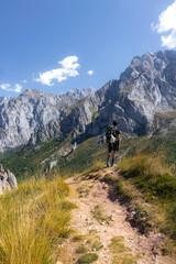 Fototapeta na wymiar Hombre joven senderista contemplando las vistas de las montañas en el parque nacional de los picos de europa dirigiendose a collado jermososo.