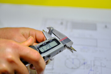 A man hand measuring the M8 bolt bonding fastener by means of calliper with blurred technical...