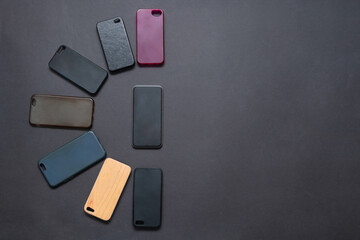 Pile of multicolored plastic back covers for mobile phone on black background. Choice of smart phone protector accessories. A lot of silicone phone backs or skins next to smart phone