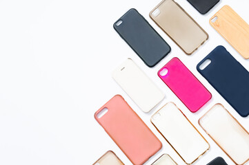 Pile of multicolored plastic back covers for mobile phone. Choice of smart phone protector accessories on white background. A lot of silicone phone backs or skins next to each other