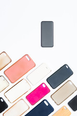 Pile of multicolored plastic back covers for mobile phone on white background. Choice of smart phone protector accessories. A lot of silicone phone backs or skins next to smart phone
