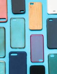 Pile of multicolored plastic back covers for mobile phone. Choice of smart phone protector accessories on blue background. A lot of silicone phone backs or skins next to each other