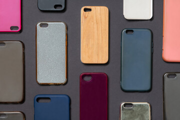 Pile of multicolored plastic back covers for mobile phone. Choice of smart phone protector accessories on black background. A lot of silicone phone backs or skins next to each other
