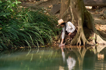 A cowgirl relaxes by a river in summer.