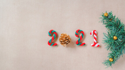 2021 from artificial golden pine cone and candy cane with green pine branch on recycled grunge brown paper , Christmas and New year background, greeting season , festive and celebration festival