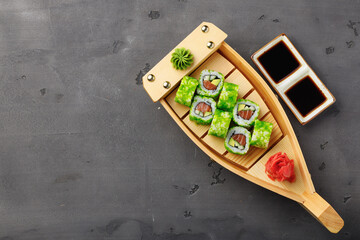 Top view of California sushi roll in plate on black background