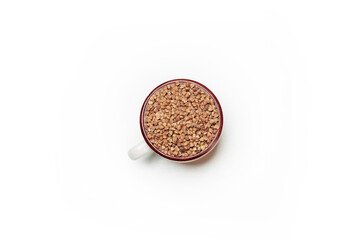 Top view of uncooked buckwheat grain seeds in the ceramic cup isolated on the white background