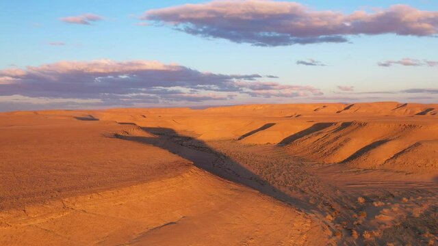 Aerial view of magical Israel desert Negev view. Panoramic landscape of the horizon with shadow terrain curves at National park. Golden red purple hour over dryland outbacks.