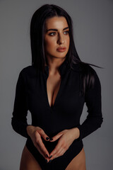 Facial portrait of a young brunette. Girl in a black bodysuit. White background.