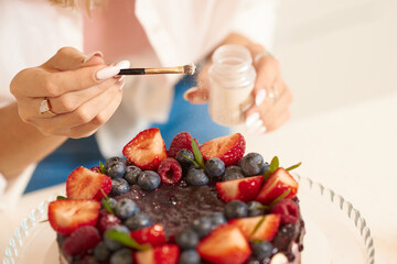 The girl decorates the cake. Close hands. Details