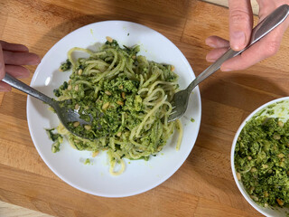 Woman putting pesto sauce on pasta