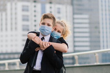 Schoolchildren, a boy and girl in medical masks walk in the city.