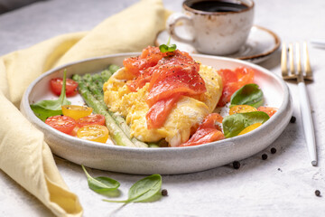 Fried eggs with green asparagus and salmon, cherry tomatoes and fresh spinach.