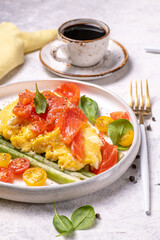 Fried eggs with green asparagus and salmon, cherry tomatoes and fresh spinach.