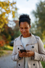 Woman using mobile phone, while walking outside.