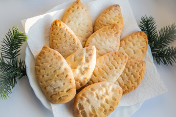 Biscuits in the form of cones on a napkin and a white plate at the edges lie twigs ate