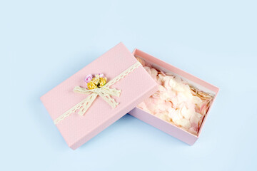 Pink gift box full of tender pink hearts of confetti on blue background. Valentine's Day, wedding, love concept. Top view, flat lay, copy space.