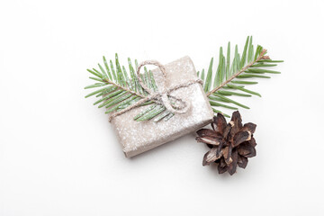 
Christmas composition. Christmas gift in craft paper, pine cones, fir branches on a white background. Flat lounger, top view, copy space
