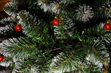 Artificial pine branches in the snow with red Christmas tree ball ornaments. Christmas decorations. Seasonal winter holiday. New year concept. New Year's mood.