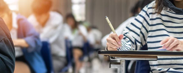 Fotobehang Exam at school with student's taking educational admission test in class, thinking hard, writing answer in university classroom, education and world literacy day concept © Chinnapong