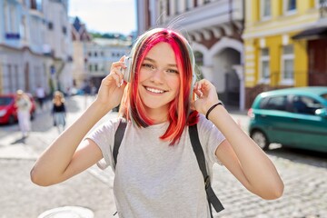 Outdoor portrait of teenage girl listening music with wireless headphones