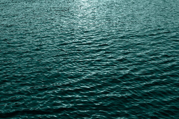 Ripples on blue transparent water in sea with sun reflection. Banner toned in trendy color of the year 2021