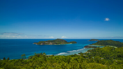 Fototapeta na wymiar Panoramic view of the densely overgrown green Seychelles washed by turquoise water, the horizon is buried in the sea.