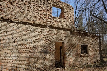 large brown brick wall of an old ruined house with empty windows and a door on the street