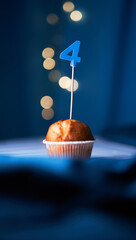 Birthday cupcake or muffin with number four (4) and lights on the blue background. Birthday or...