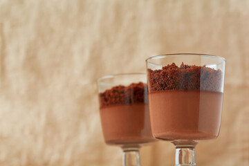 Delicious dessert chocolate mousse with brownie in glass jars on a light slate, stone or concrete background. Selective focus.