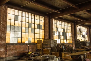 Zelfklevend Fotobehang Long brick wall with frosted windows of an abandoned factory with debris left on the floor in the deep south © Richard