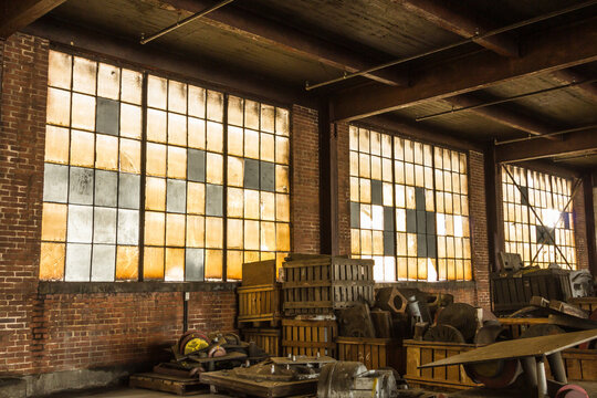 Long brick wall with frosted windows of an abandoned factory with debris left on the floor in the deep south
